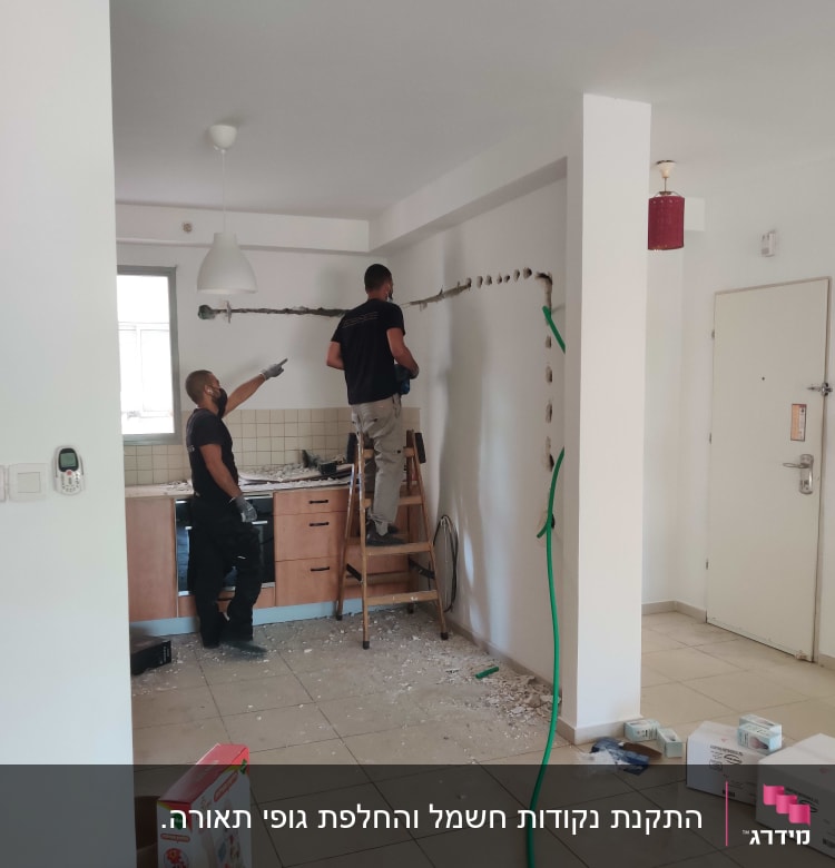 שני חשמלאים עובדים על קיר עם סולם וכלים